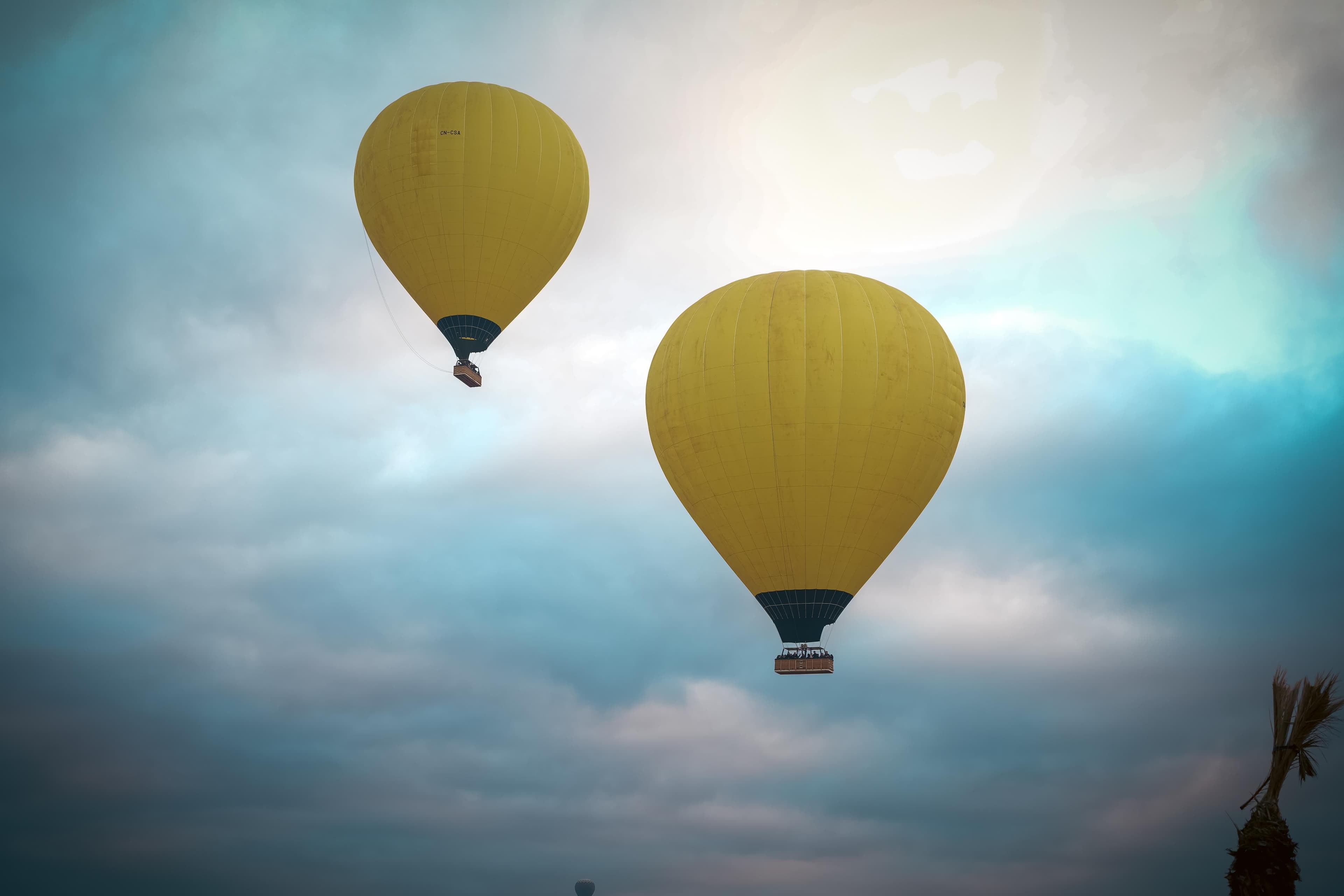 Hot air balloons in a soft pink sunrise sky over Marrakech